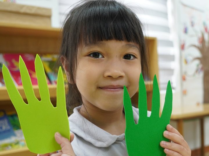A child holding up two hand shapes she cut from foam